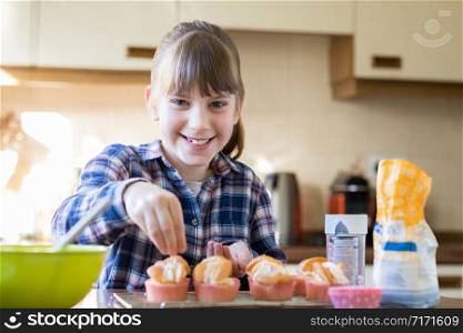 Portrait Of Girl In Kitchen Decorating Home Made Cupcakes