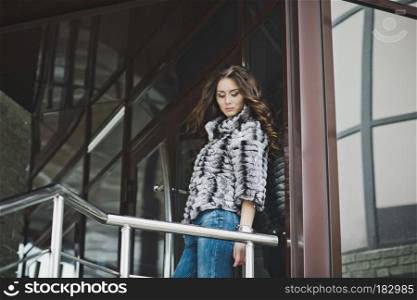 Portrait of girl in winter clothes front of the building.. Girl standing near the stairs 4991.