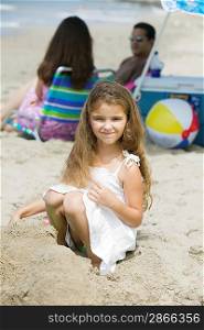 Portrait of girl on beach, parents in background