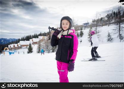 Portrait of girl posing on top of ski slope with ski equipment