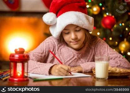 Portrait of girl sitting at fireplace and writing letter to Santa