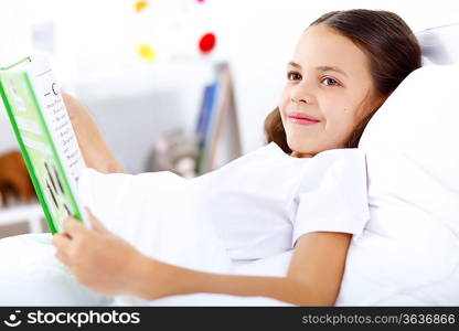 Portrait of girl with a book in bed at home