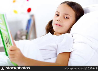 Portrait of girl with a book in bed at home