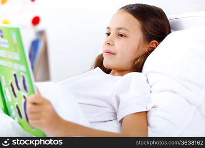 Portrait of girl with a book in bed at home