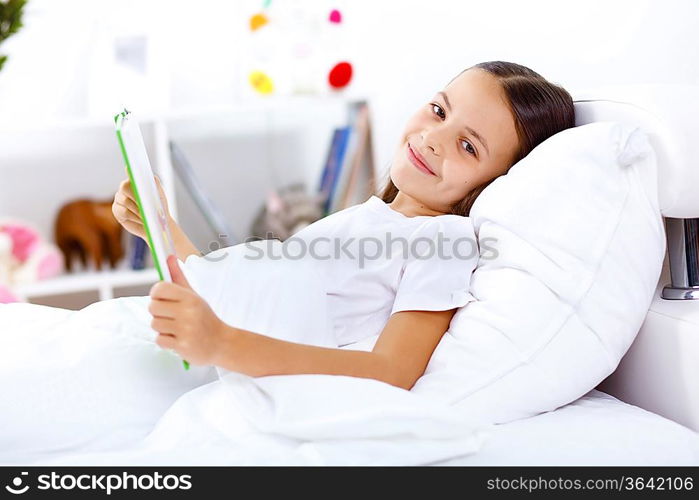 Portrait of girl with a book in bed at home