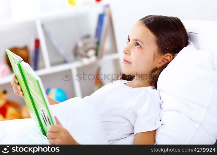 Portrait of girl with a book in bed at home