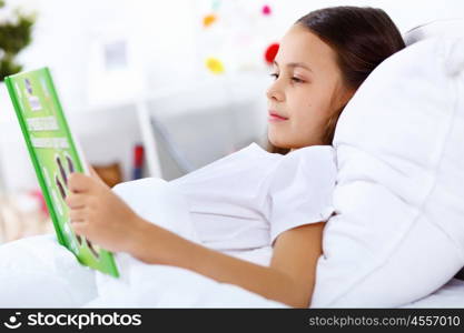 Portrait of girl with a book in bed at home