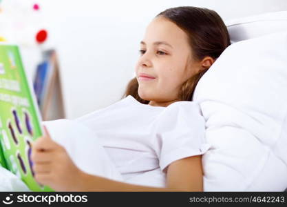 Portrait of girl with a book in bed at home