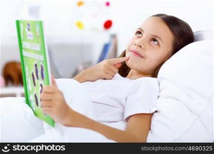 Portrait of girl with a book in bed at home