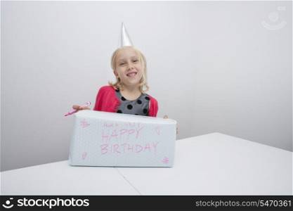 Portrait of girl with birthday present at table in house