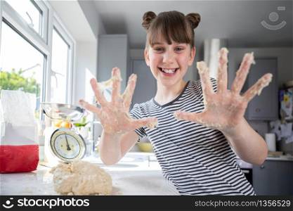 Portrait Of Girl With Messy Hands Having Fun In Kitchen Kneading Dough For Baking