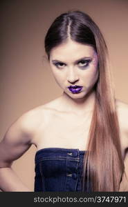 Portrait of girl young woman with long straight hair and creative makeup in jeans corset on brown. Studio shot.