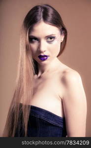 Portrait of girl young woman with long straight hair and creative makeup in jeans corset on brown. Studio shot.