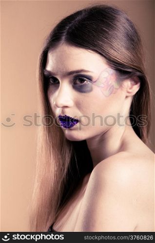 Portrait of girl young woman with long straight hair and creative makeup on brown. Studio shot.