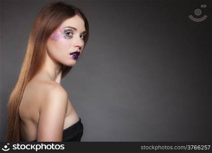 Portrait of girl young woman with long straight hair and creative makeup on dark. Blank copy space. Studio shot.