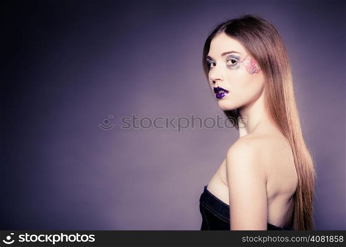 Portrait of girl young woman with long straight hair and creative makeup on violet. Blank copy space. Studio shot.