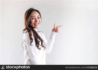 Portrait of good-looking beautiful young asian adult girl wearing white sweater for winter pointing to blank copy space on white background