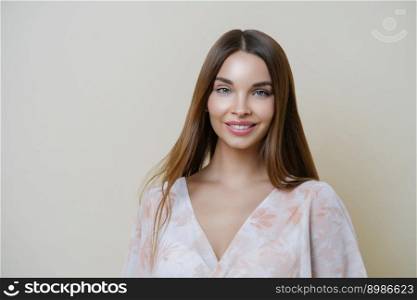 Portrait of good looking dark haired European woman wears stylish clothes, applies makeup, isolated over brown background, has natural look, fresh clean skin. Beauty and health lifestyle concept.