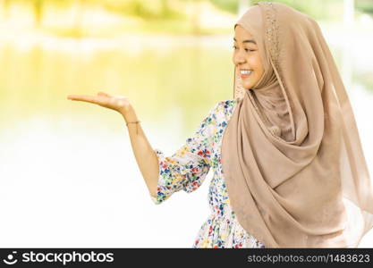 Portrait of good-looking Happy young teenager Muslim islamic asian university girl with hand up on copyspace