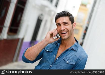Portrait of good looking man in urban background talking on phone