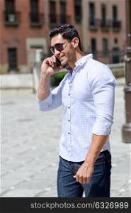Portrait of good looking man in urban background talking on phone