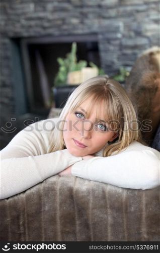 portrait of good-looking young blonde in chalet with face resting in arms