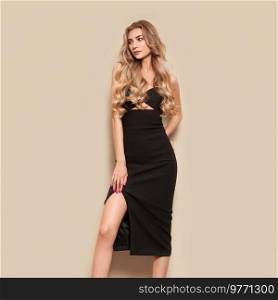 Portrait of gorgeous elegant sensual blonde woman wearing fashion black dress isolated on white background. Model woman with long curly hairstyle. Care and beauty hair product