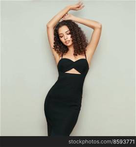 Portrait of gorgeous elegant sensual woman wearing fashion black dress. Brunette woman with a hairstyle in the style of Afro curls. Care and beauty. Fashion photo