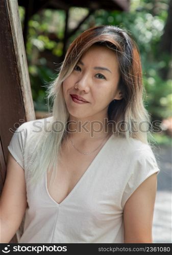 Portrait of gorgeous young woman long blond and white hair in cream dress at wooden house terrace. Resting leisure concept, Selective focus.
