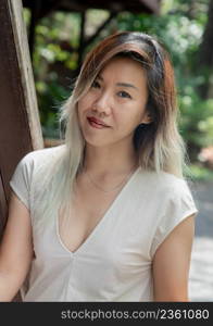 Portrait of gorgeous young woman long blond and white hair in cream dress at wooden house terrace. Resting leisure concept, Selective focus.