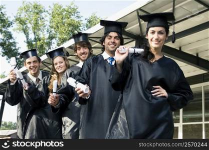 Portrait of graduate students holding their degrees and smiling