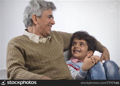 Portrait of grandfather and grandson sitting on sofa