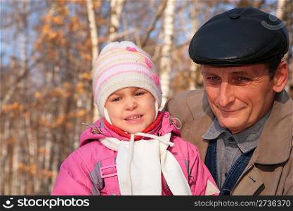 Portrait of grandfather with granddaughter in wood in autumn