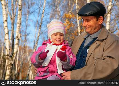 Portrait of grandfather with granddaughter in wood in autumn