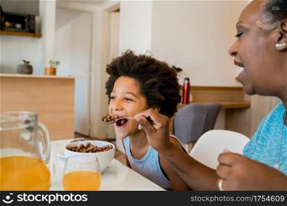 Portrait of grandmother and grandchild having breakfast together at home. Family and lifestyle concept.