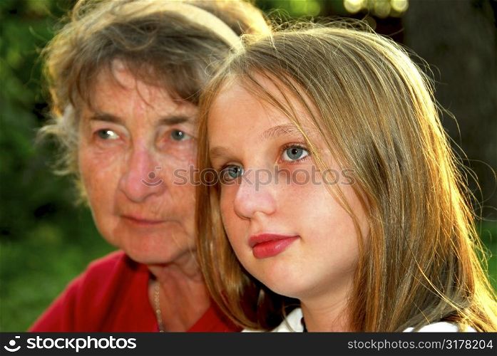 Portrait of grandmother and granddaughter in summer park, focus on the girl
