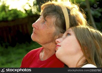 Portrait of grandmother and granddaughter in summer park looking up