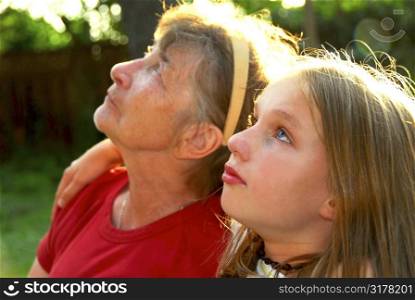 Portrait of grandmother and granddaughter in summer park looking up