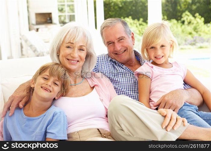 Portrait Of Grandparents With Grandchildren Relaxing Together On Sofa