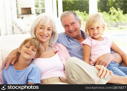 Portrait Of Grandparents With Grandchildren Relaxing Together On Sofa