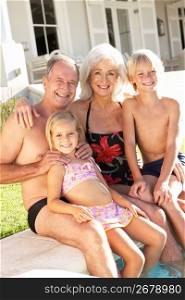 Portrait Of Grandparents With Grandchildren Sitting Together By Swimming Pool