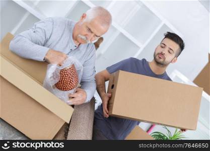 portrait of grandson helping grandfather moving into new home