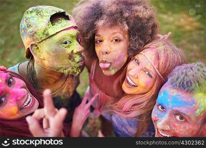 Portrait of group of friends at festival, covered in colourful powder paint