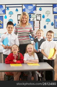 Portrait Of Group Of Primary Schoolchildren And Teacher Sitting At Desk In Classroom