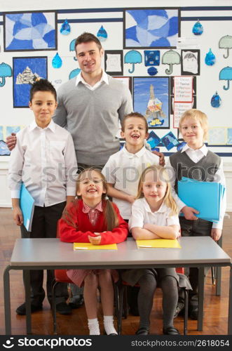 Portrait Of Group Of Primary Schoolchildren And Teacher Sitting At Desk In Classroom