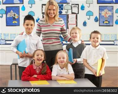 Portrait Of Group Of Primary Schoolchildren And Teacher Sitting At Desk In Classroom