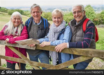 Portrait Of Group Of Senior Friends Hiking In Countryside Standing By Gate