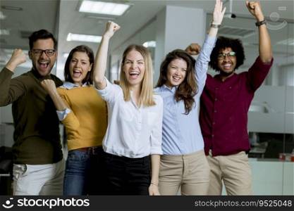 Portrait of group of young excited business people with hands up standing in office