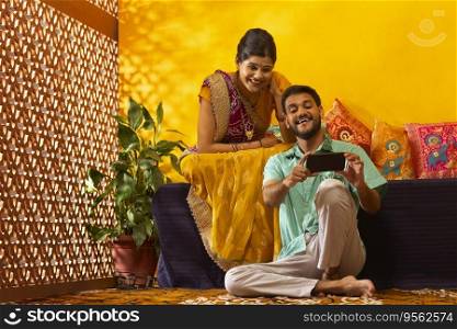 Portrait of Gujrati couple watching movie on smartphone