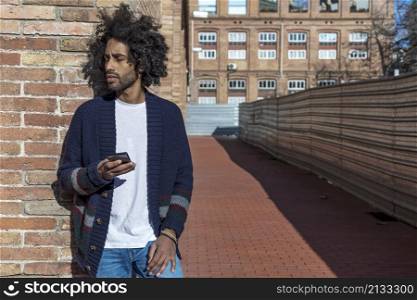Portrait of handsome afro man using his mobile in the street.